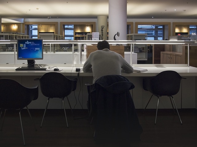 Image depicts a man working late into the evening, symbolizing workaholism.